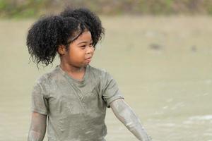 Little girls have fun playing in the mud in the community fields photo