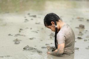 Children have fun playing in the mud in the community fields and catching a frog in a muddy field. photo