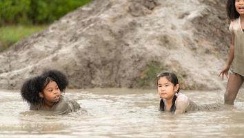 Little girls have fun playing in the mud in the community fields photo