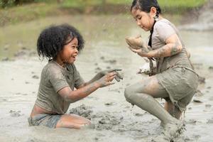 los niños se divierten jugando en el lodo en los campos comunitarios y atrapando una rana en un lodo. foto