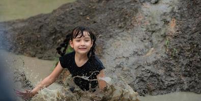 Little girls have fun playing in the mud in the community fields photo