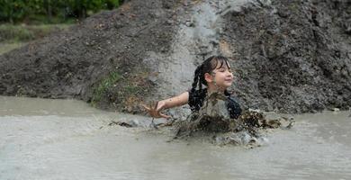 las niñas se divierten jugando en el barro en los campos comunitarios foto