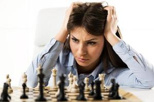 joven empresaria preocupada frente al tablero de ajedrez foto