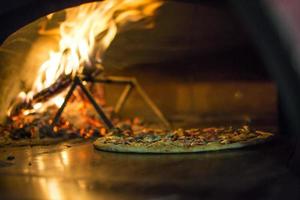 Pizza near the stone stove with fire. Background of a traditional pizzeria restaurant with a fire place. photo