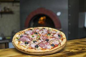 Pizza near the stone stove with fire. Background of a traditional pizzeria restaurant with a fire place. photo