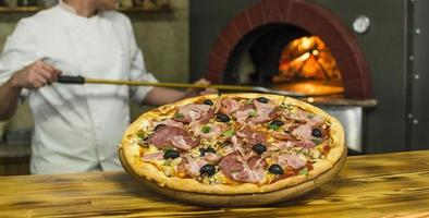 Pizza near the stone stove with fire. Background of a traditional pizzeria restaurant with a fire place. photo