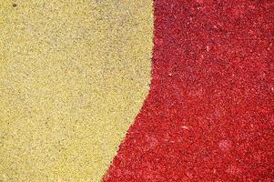 Yellow and red bright soft soft rubber flooring safe for sports and workout or on the playground from the many small round pebbles pressed. Background, texture photo