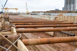 A large huge ditch pit tunnel with reinforcing structures from thick iron pipes of beams and structures at the construction site of the underground metro station line photo