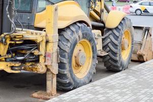 tractor de excavadora pesada industrial de gran alcance amarillo brillante, bulldozer, equipo de construcción especializado para la reparación de carreteras durante la construcción de un nuevo microdistrito en una gran ciudad foto