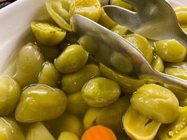 Delicious green natural fresh marinated wholesome tomatoes in a plate with tongs photo