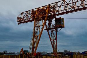 construcción de carga de hierro de metal amarillo pesado pesado grúa de pórtico potente industrial estacionaria de tipo puente sobre soportes para levantar carga en un sitio de construcción moderno de edificios y casas foto