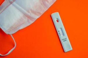 test for coronavirus on an orange background. on a matte background a sensitive strip for coronavirus, a mask. taking care of your health, assessing your health photo