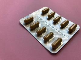 Medical pharmaceutical brown medications for the treatment of diseases and the killing of microbes and viruses tablets and vitamins blisters blisters from coronavirus covid-19 on a pink background photo