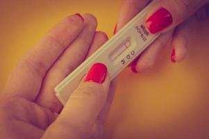 test for coronavirus on an orange background. medical analysis. a girl with a bright red manicure holds a coronavirus antibody test on her fingers photo