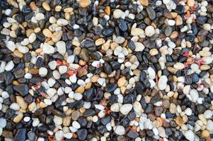 Texture of different unusual stones wet with water from different colors black white red yellow brown natural round. The background photo