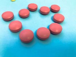 productos farmacéuticos farmacéuticos médicos redondos rojos para el tratamiento de enfermedades píldoras medicamentos sobre un fondo azul foto