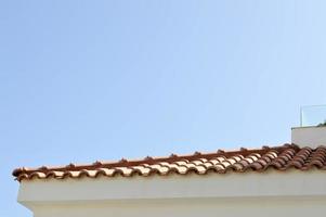 The texture of a red tiled roof with red tiles against the blue sky and copy space photo