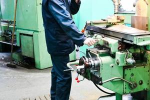 un trabajador masculino trabaja en un torno de cerrajería de hierro metálico más grande, equipo para reparaciones, trabajo de metal en un taller en una planta metalúrgica en una producción de reparación foto