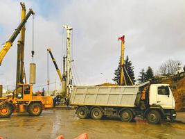 construction equipment at the overpass repair site. high, the crane holds the pile for the construction of a huge overpass. next to a heavy truck with a gray body photo