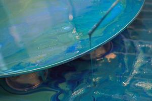 The process of creating a home-made trendy abstract modern pattern painted with a brush of acrylic blue multi-colored resin on a round wooden board photo