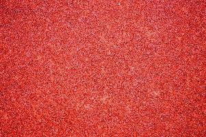 Red bright soft rubber flooring safe for sports and workout or on the playground from the many small round pebbles pressed. Background, texture photo