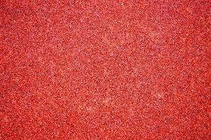 Red bright soft rubber flooring safe for sports and workout or on the playground from the many small round pebbles pressed. Background, texture photo