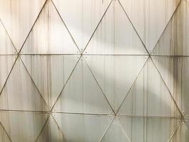 textura de pared blanca de hierro industrial de placas triangulares con costuras con patrones al estilo de triangulación con remaches. el fondo foto