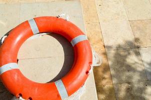 el aro salvavidas naranja para la seguridad de la natación se encuentra en el suelo de piedra en un exótico complejo marino tropical cálido del sur foto