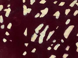 Texture of dark red maroon stone old cracked wall painted with paint with white spots, dots. The background photo