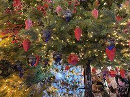 ramas verdes de un esponjoso árbol navideño festivo de año nuevo con juguetes en bolas y bombillas y guirnaldas brillantes, fondo foto