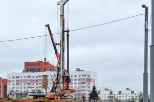 A large powerful iron pile driver, an industrial construction machine designed for lifting, installing piles at the point of immersion in the ground at the construction site of buildings and houses photo