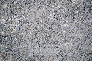 Gray asphalt road with small pebbles and cracks. Texture, background photo