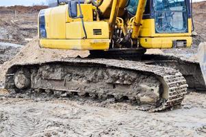 tractor de excavadora pesada industrial de gran alcance amarillo brillante, bulldozer, equipo de construcción especializado para la reparación de carreteras durante la construcción de un nuevo microdistrito en una gran ciudad foto