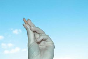 female hand with manicure holds an oval tablet against the sky. black and white hand with medicine. Artistic picture of taking pills, medical substances. background for drugs photo