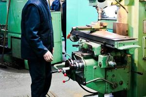 A male worker works on a larger metal iron locksmith lathe, equipment for repairs, metal work in a workshop at a metallurgical plant in a repair production photo