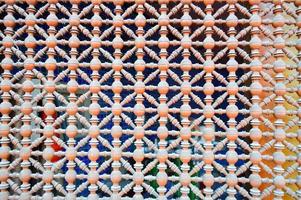 Texture of a wooden brown grating with holes on the window in Arabic style. The background photo