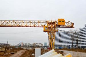 High heavy yellow metal iron load-bearing construction stationary industrial powerful gantry crane of bridge type on supports for lifting cargo on a modern construction site of buildings and houses photo