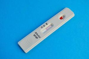 coronavirus test lies on a blue background. a drop of venous blood on the test strip. express diagnostics of coronavirus. the test shows the presence of IgG and IgM antibodies photo