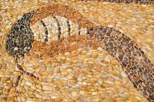 The texture of the stone wall, the road from small round and oval stones with abstracted lines of snake patterns with sandy seams of natural old yellow black brown. The background photo