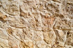 Texture of a stone wall, roads from stones, bricks, cobblestones, tiles with sandy seams of gray ancient natural old yellow with sharp edges. The background photo