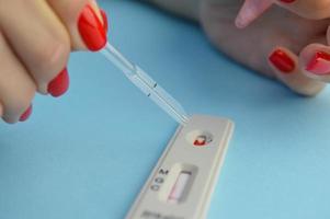 test for coronavirus on a blue background. girl with a bright red manicure makes a blood test. a drop of blood on the sensitive test strip photo