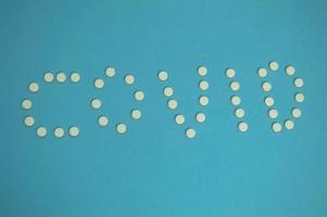 medicinal products are laid out in the form of a coronavirus. white pills on a blue background. Means for strengthening immunity from infectious diseases. the tablets are shot from above photo