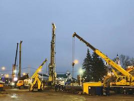 construction equipment at the overpass repair site. tall, yellow, metal crane carries large concrete blocks to great heights photo