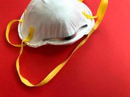 on a bright red white background a respirator with retainers on his face. protection of the respiratory system in emergency situations and contacts with chemical compounds photo