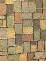 textura de hermosas baldosas de ladrillo de pavimentación de hormigón de piedra rectangular multicolor con costuras cubiertas de hierba verde. el fondo foto