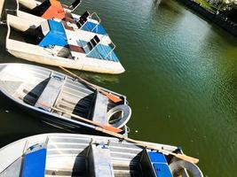 botes y catamaranes en un lago estanque en un canal fluvial con agua de flores verdes están amarrados en la orilla foto