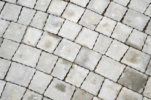 Gray stone walkway made of concrete cement square diagonal paving slabs with seams. Texture, background photo
