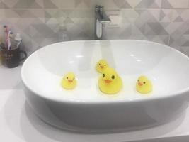 the yellow duck family swims in the sink due to pollution of the oceans and waters. environmental pollution and lack of natural resources. rubber toy ducks bathe in the bath. photo