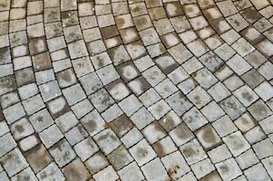 Gray stone walkway made of concrete cement square diagonal paving slabs with seams. Texture, background photo