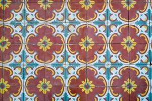 The texture of square ceramic tiles with patterns from traditional Arabic ornaments and flowers of yellow and blue with seams. The background photo